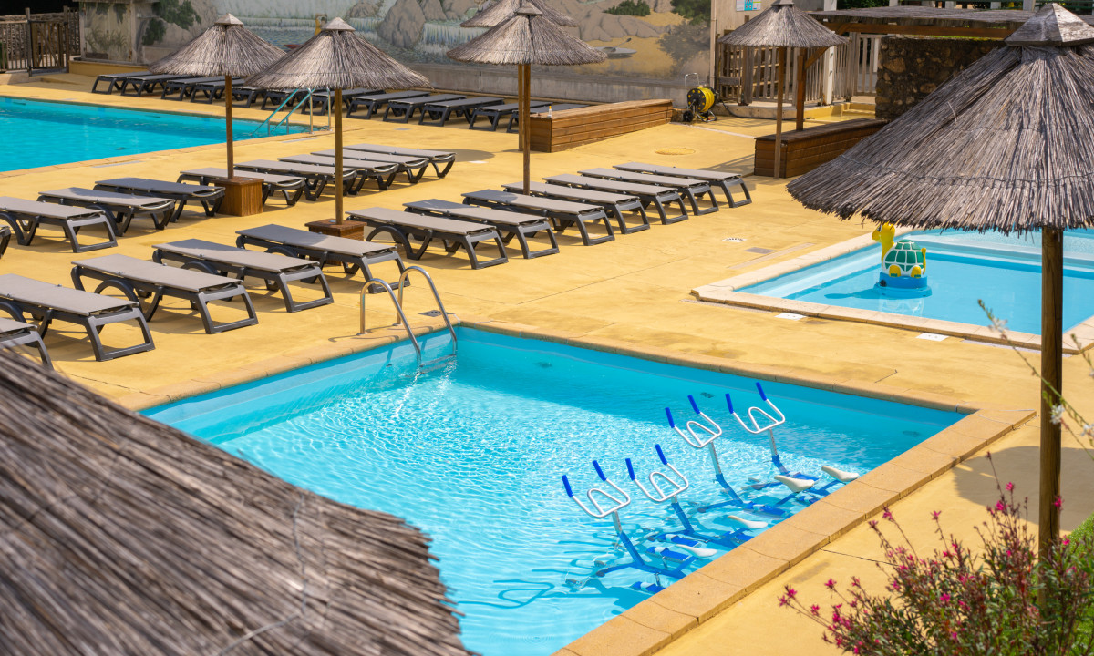 At La Clémentine, poolside reclining chairs beneath straw umbrellas are accompanied by exercise bicycles immersed in water.