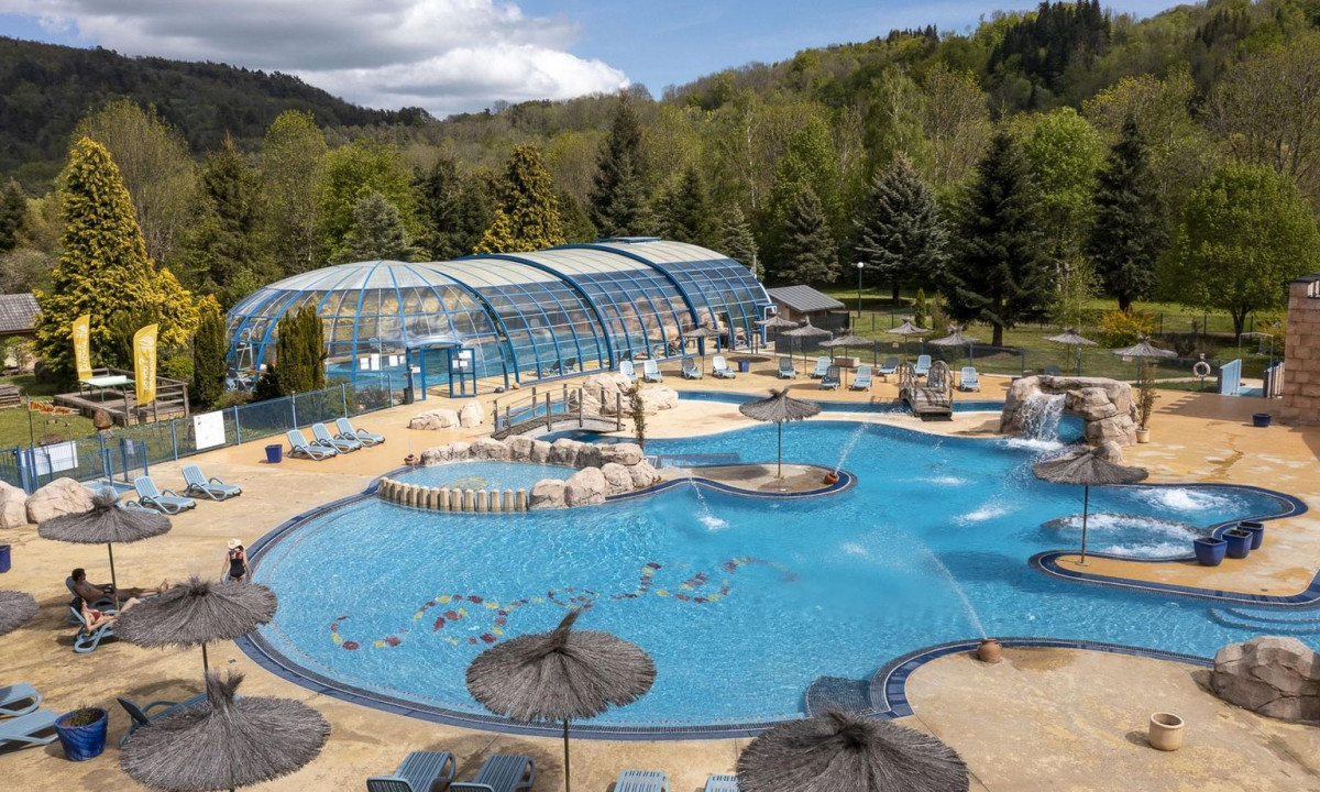 Outdoor pool with loungers, water features, surrounded by trees and hills at La Ribeyre
