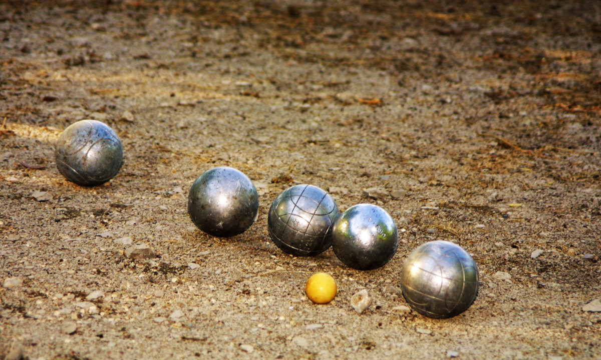 At La Clémentine, metallic balls are positioned on a sandy ground, encircling a smaller yellow target ball.