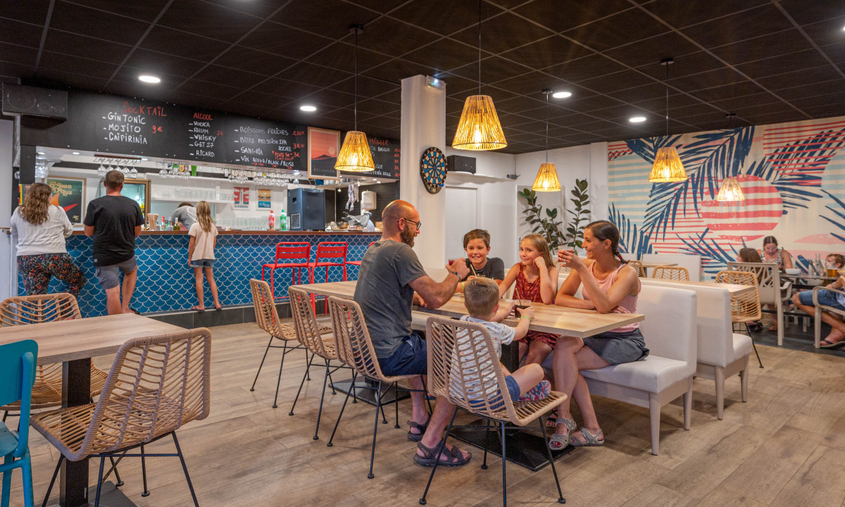Family dining at a cafe inside an indoor setting with wooden furniture and tropical-themed decor at Atlantica