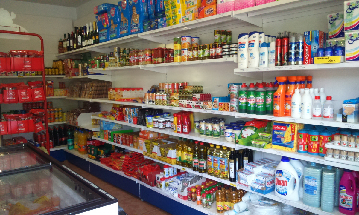 Shelves stocked with various grocery items, drinks, and household supplies inside a small store at Resort Els Pins