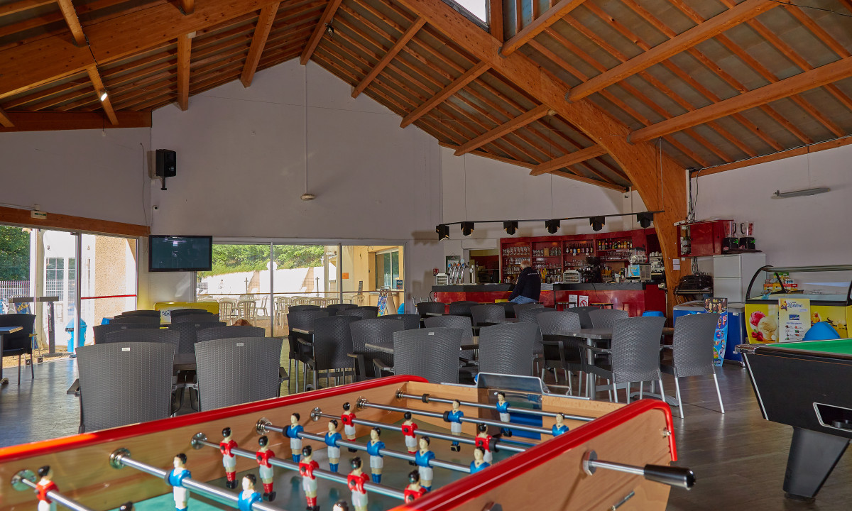 At Terrasses du Lac, there is a foosball table and a billiards table in a leisure space featuring a bar and seating.