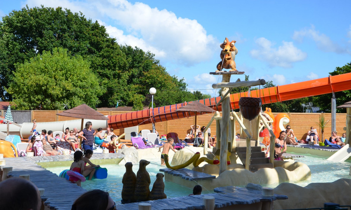 At Le Domaine de Léveno, kids and adults are enjoying themselves in a water park featuring slides and animal sculptures.
