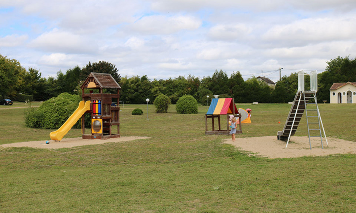 At Le Petit Trianon, a child plays beneath a vibrant canopy in a grassy area, surrounded by slides and play structures.