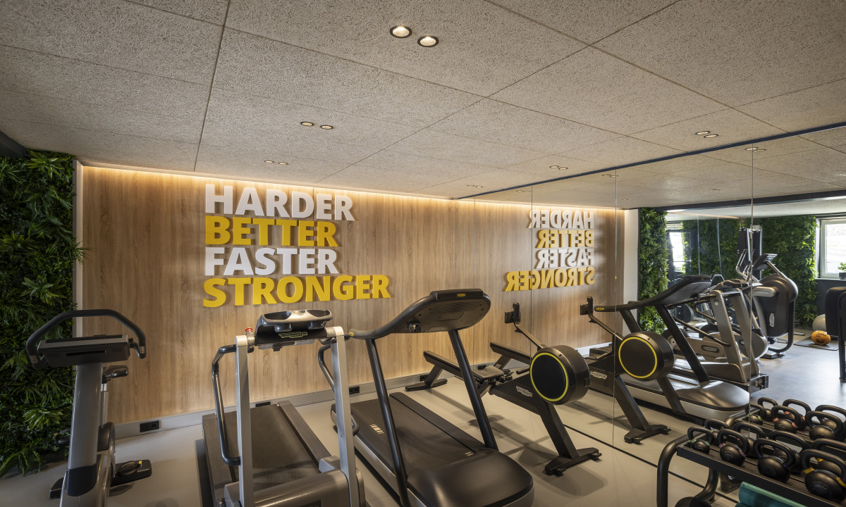 Gym equipment sits unused in a modern, well-lit room with motivational words on the wall; surrounded by greenery at Kesselspitze Valamar Collection Hotel