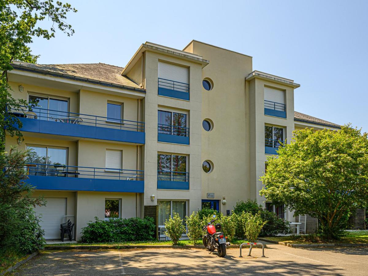 Modern apartment building with balconies; motorcycle parked; sidewalks and lush greenery; sunny day at Ker Goh Lenn
