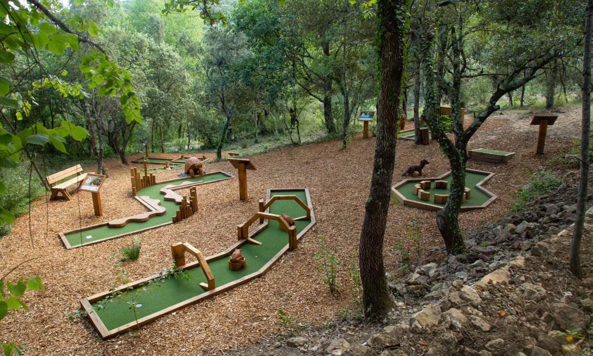 Mini-golf course in the middle of a wooded area with various obstacles, benches, and informational boards at Domaine de Sévenier