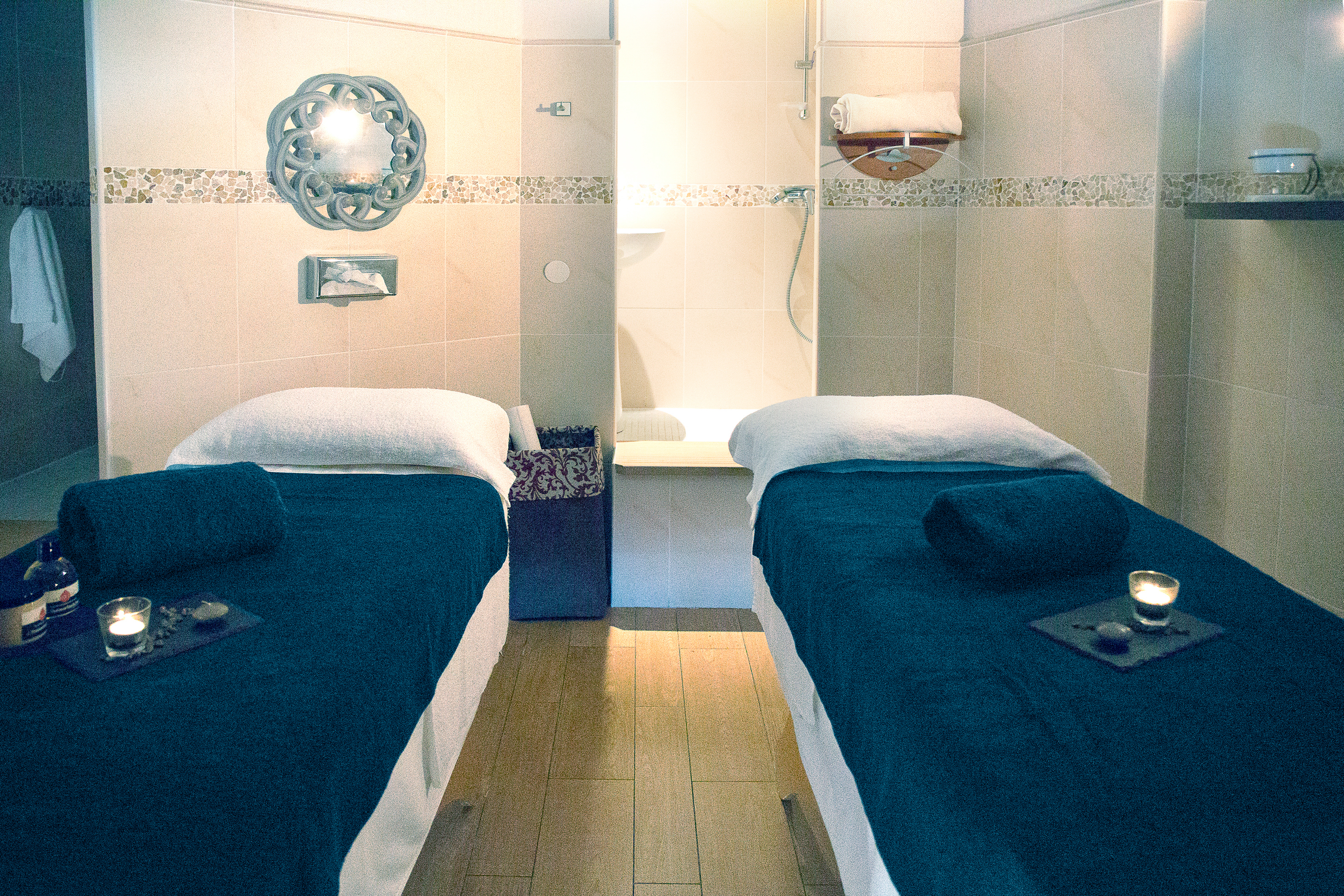 Two massage tables with rolled towels and lit candles, set in a warmly lit spa room at Les Bulles de Mer