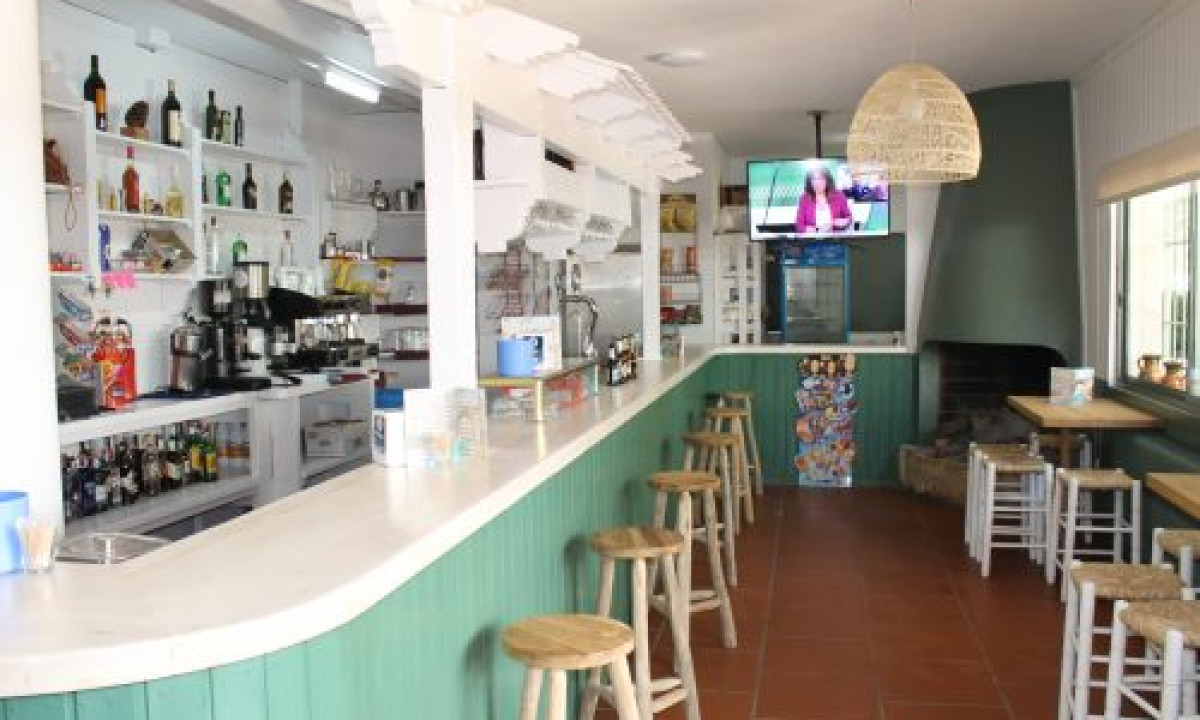 At Puente de las Herrerías, there is a bar counter with stools showcasing drinks and a television screen, situated in a well-lit, relaxed indoor environment.