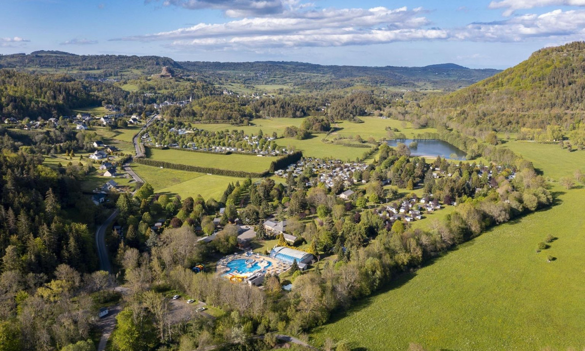 Aerial view of green countryside with campsites, pools, and scattered buildings amid forests and hills at La Ribeyre