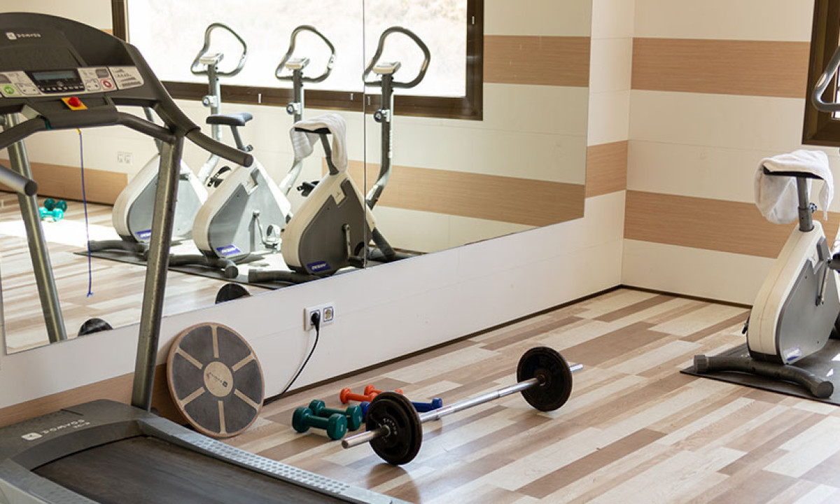 At Camping Los Escullos, exercise apparatus remains unused in a mirrored fitness room featuring bicycles and weights.