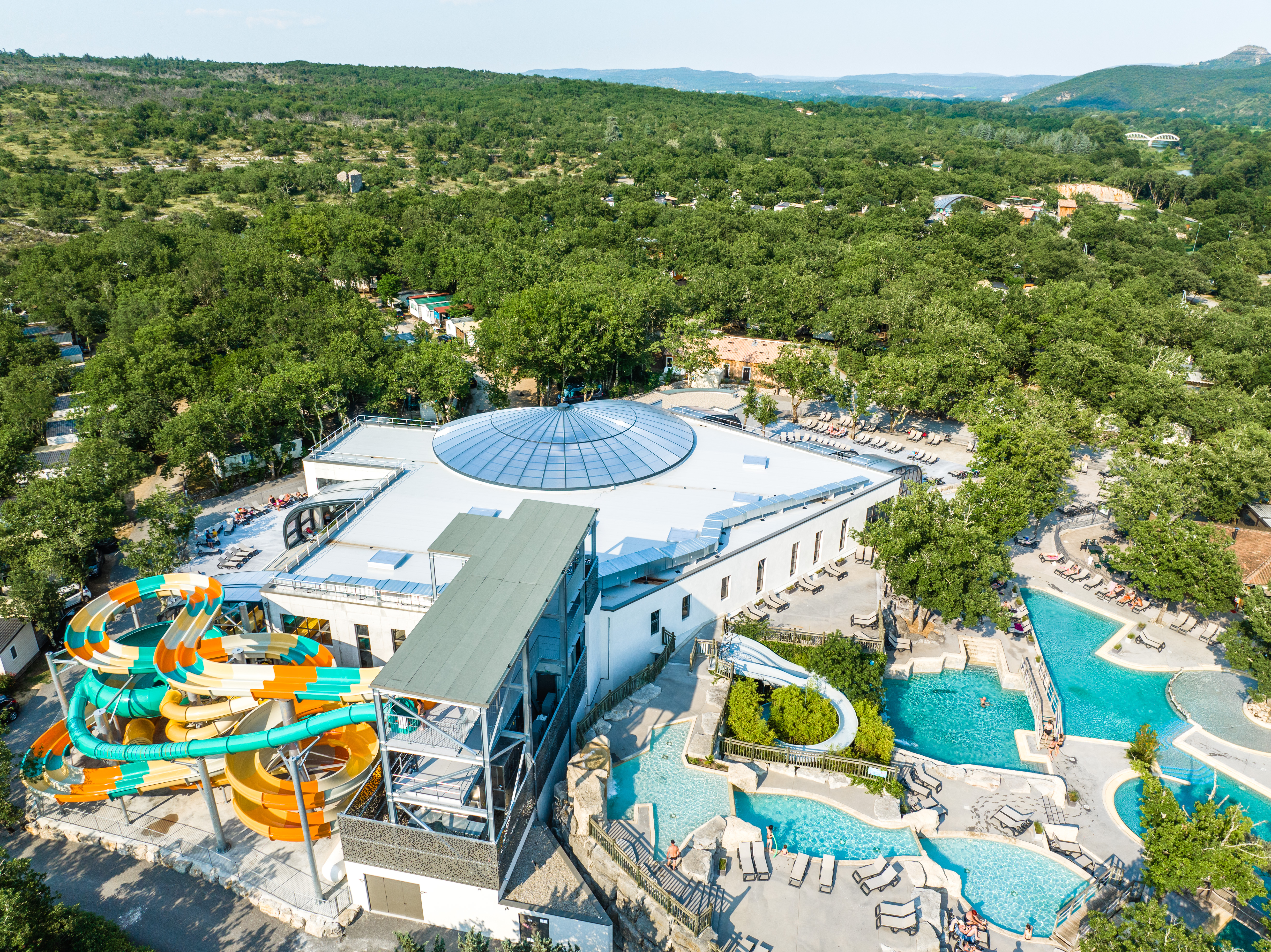 At Le Ranc Davaine, there is an expansive waterpark facility featuring vibrant slides, open-air swimming pools, and encircled by wooded hills.