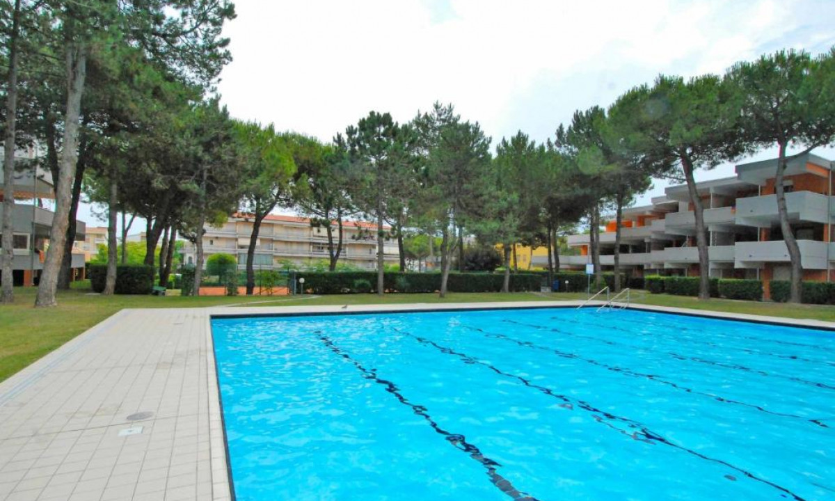Swimming pool surrounded by trees and buildings, with no people in sight at Solarium