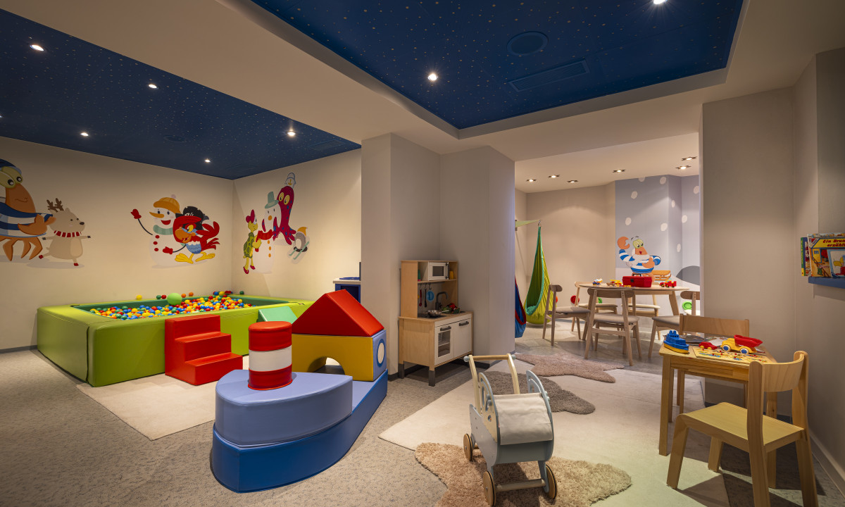 Playroom with colorful toys and furniture, featuring a ball pit and wall murals in a vibrant, well-lit space at Kesselspitze Valamar Collection Hotel