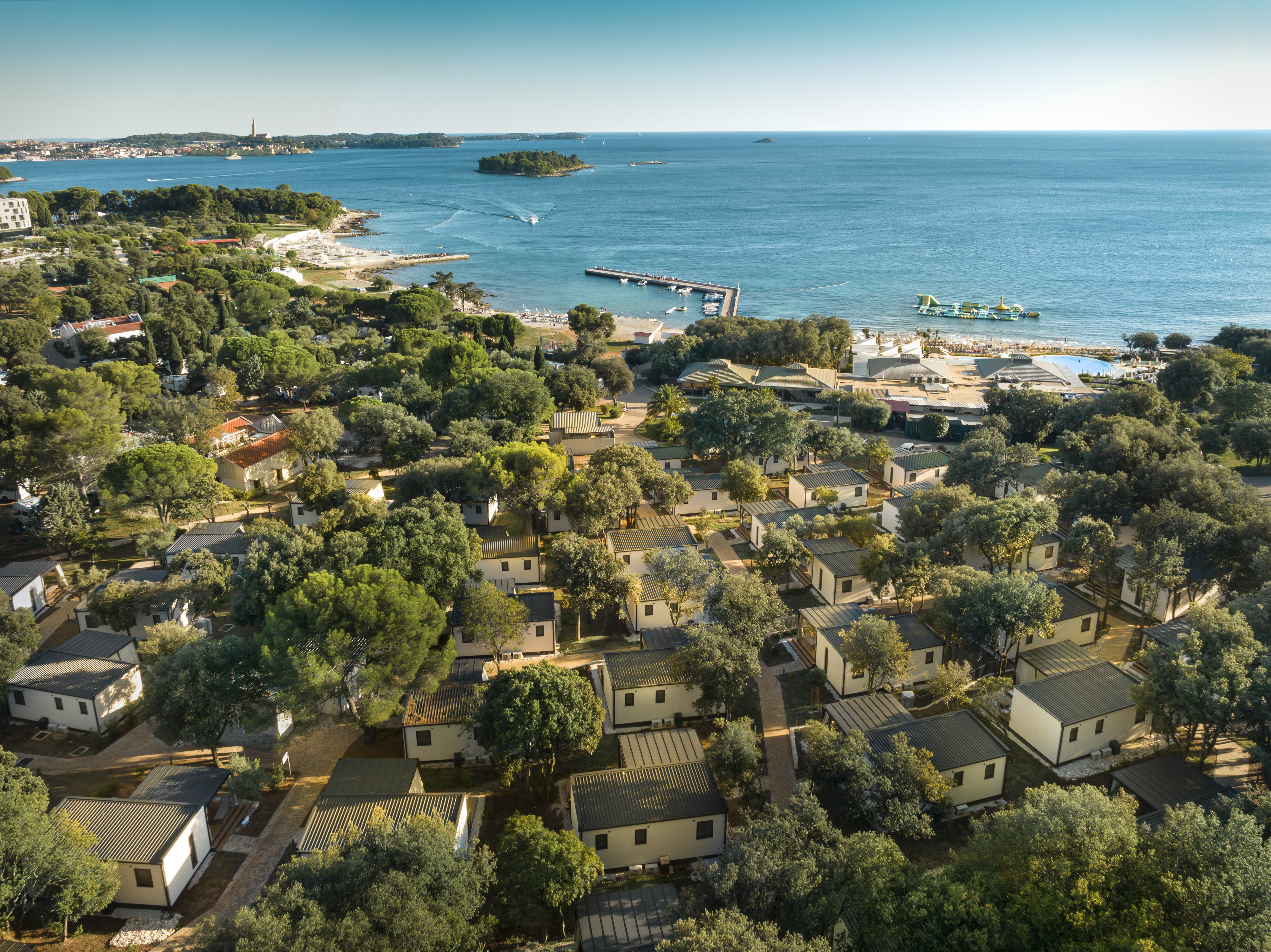 At Amarin, a bird's-eye perspective reveals cabins tucked away among the trees close to the sea, featuring a pier and vessels.