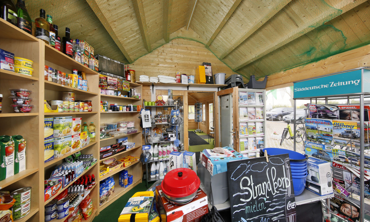 At KNAUS Campingpark Rügen, store racks exhibit an assortment of items in a wooden lodge; a diverse range of products is systematically arranged.