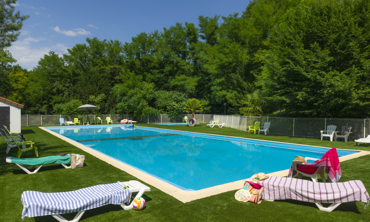At Coucou, the swimming pool remains motionless, encircled by deck chairs and lush vegetation, beneath a clear blue sky.
