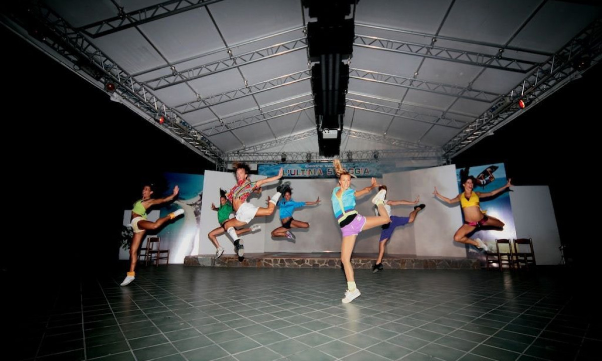 At Ultima Spiaggia, performers execute airborne jumps on a platform beneath a canopy-like framework.