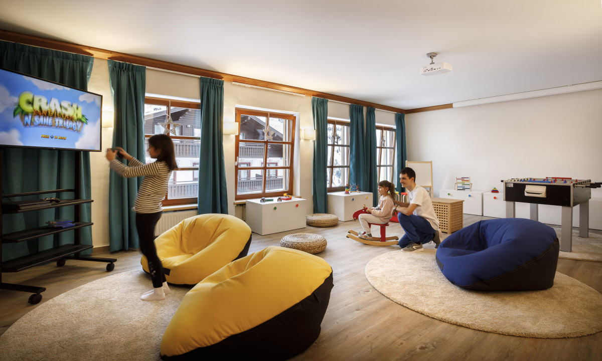 Children play in a cozy room with bean bags, TV, and toys; bright windows light the space at Valamar Obertauern Hotel