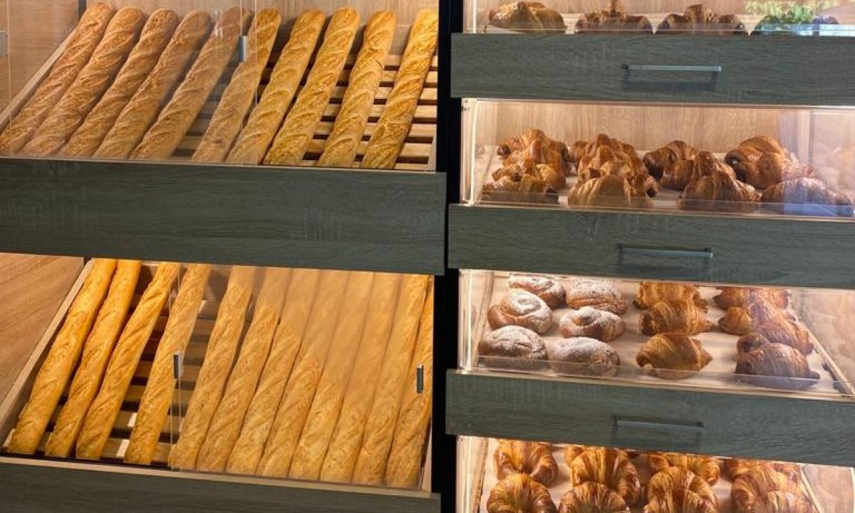 Baguettes and assorted pastries displayed in a wooden bakery case at Resort Els Pins