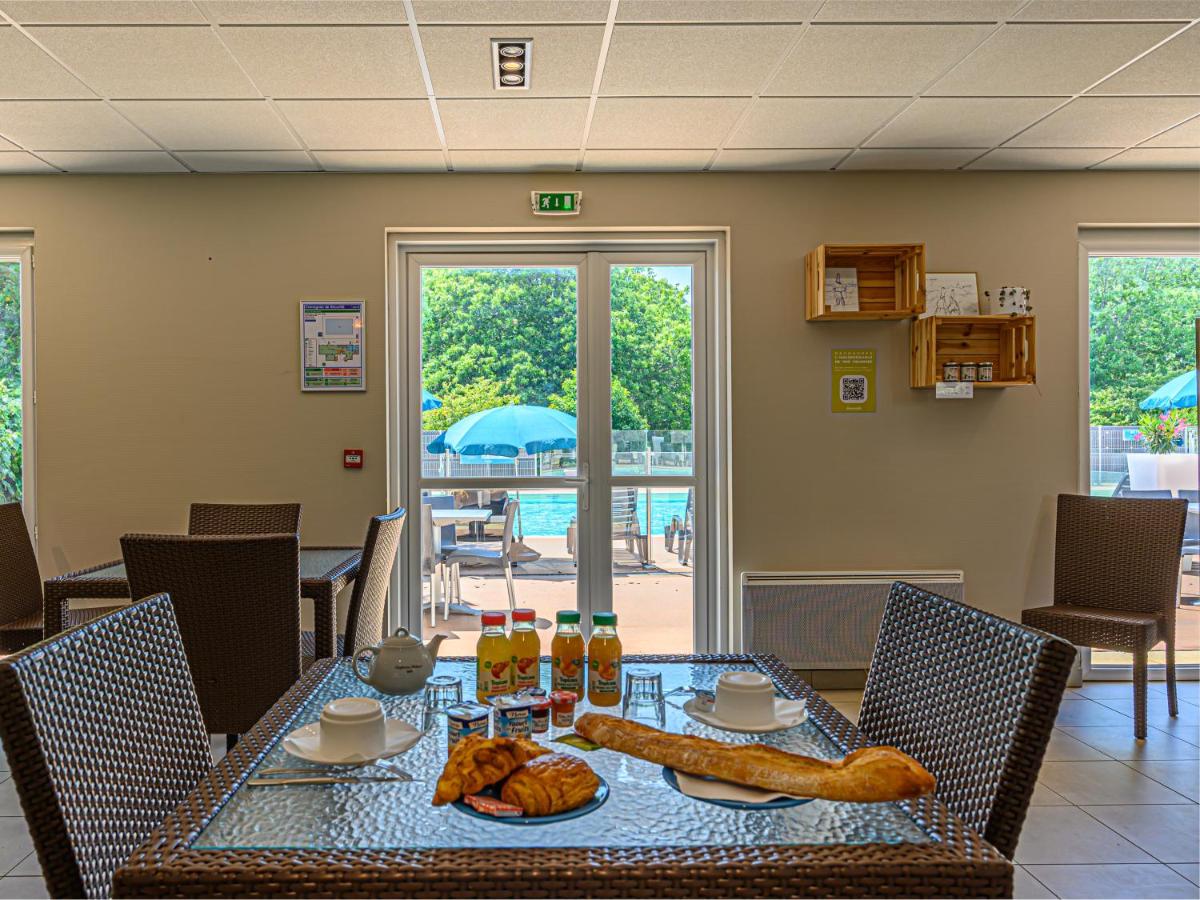 Breakfast spread on table inside cafe, overlooking pool area with blue umbrellas and greenery through glass doors at Ker Goh Lenn