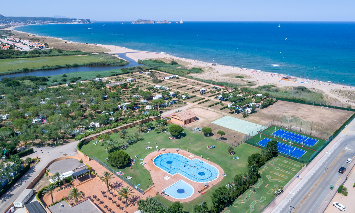 A campsite with a swimming pool and sports courts near a beach, seen from above on a sunny day at camping Playa Brava at Playa Brava
