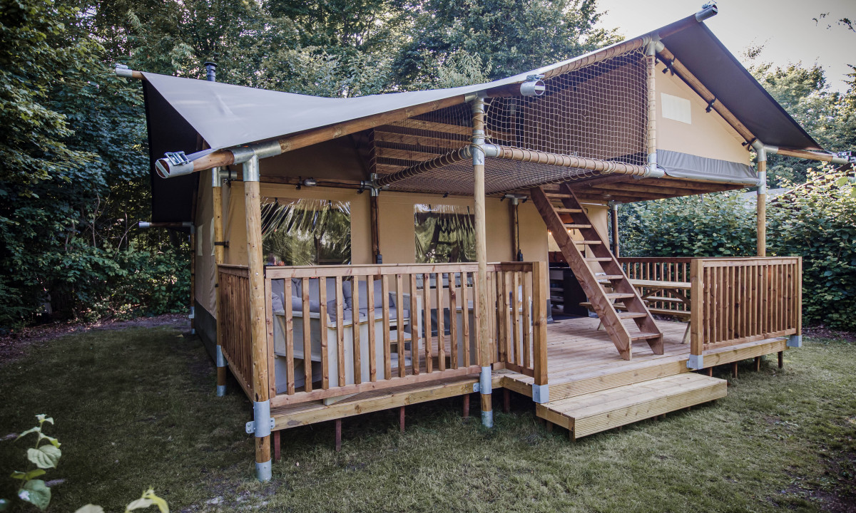 At De Baalse Hei, there is a timber cabin featuring a covered porch and an upper loft, located in a wooded region.