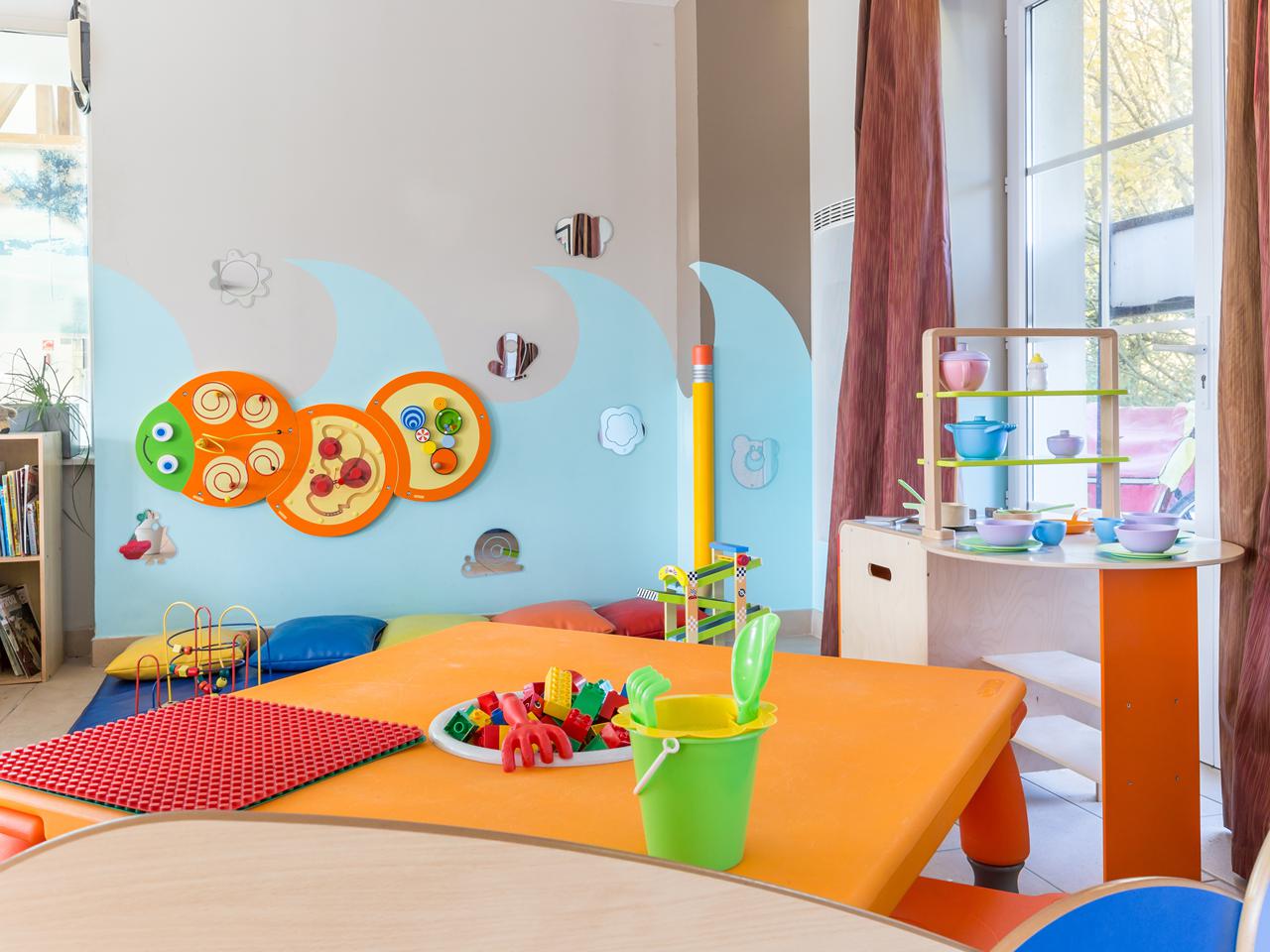 Colorful children’s play area with toys, games, and a wall maze, set in a brightly lit room at Le Green Beach