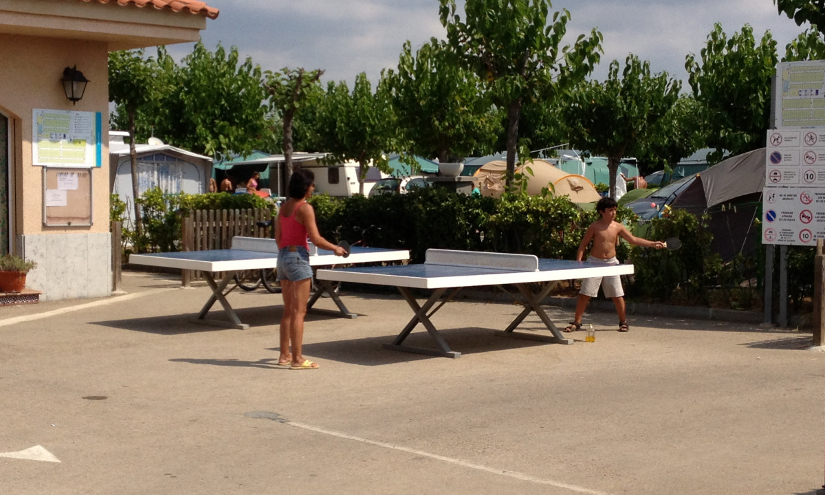 Two people playing table tennis outdoors, with tents and greenery around at Resort Els Pins