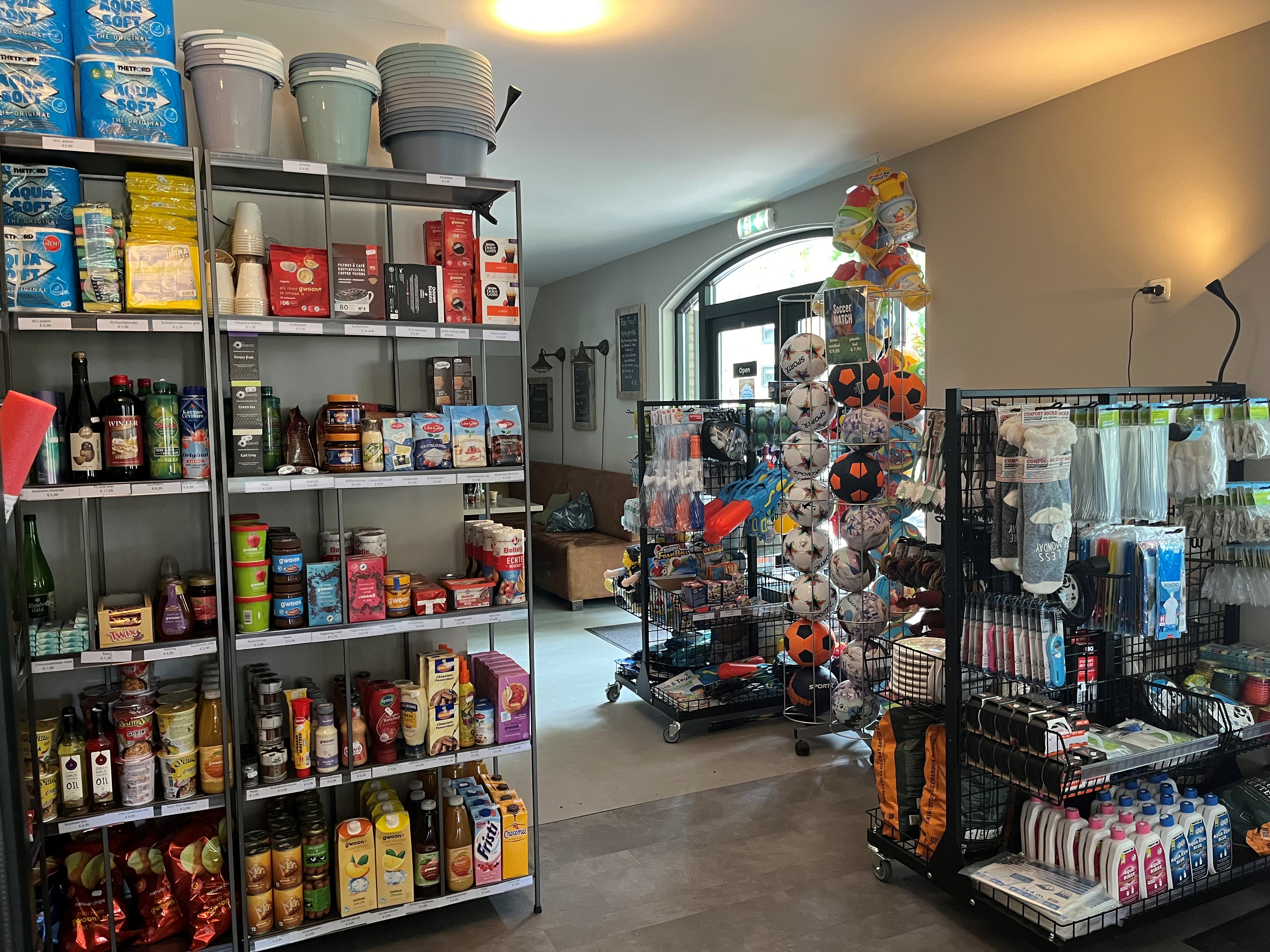 At de Vinkenkamp, store racks showcase a variety of food products, home essentials, and athletic gear; the indoor environment is well-lit.