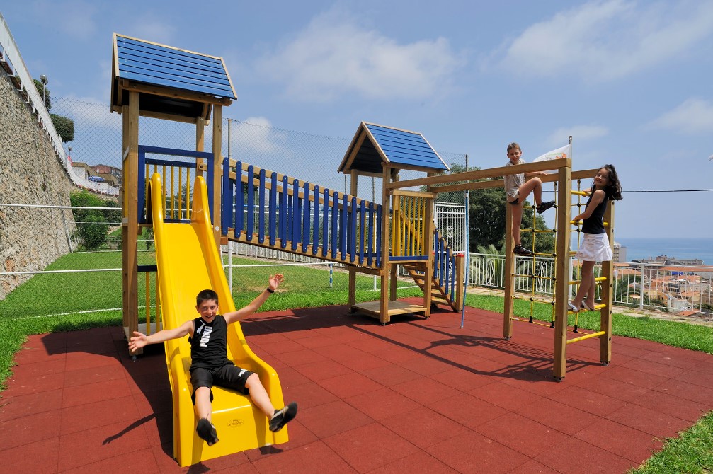 Children playing on a colorful playground structure with slide and ladder at Sant' Anna Residence