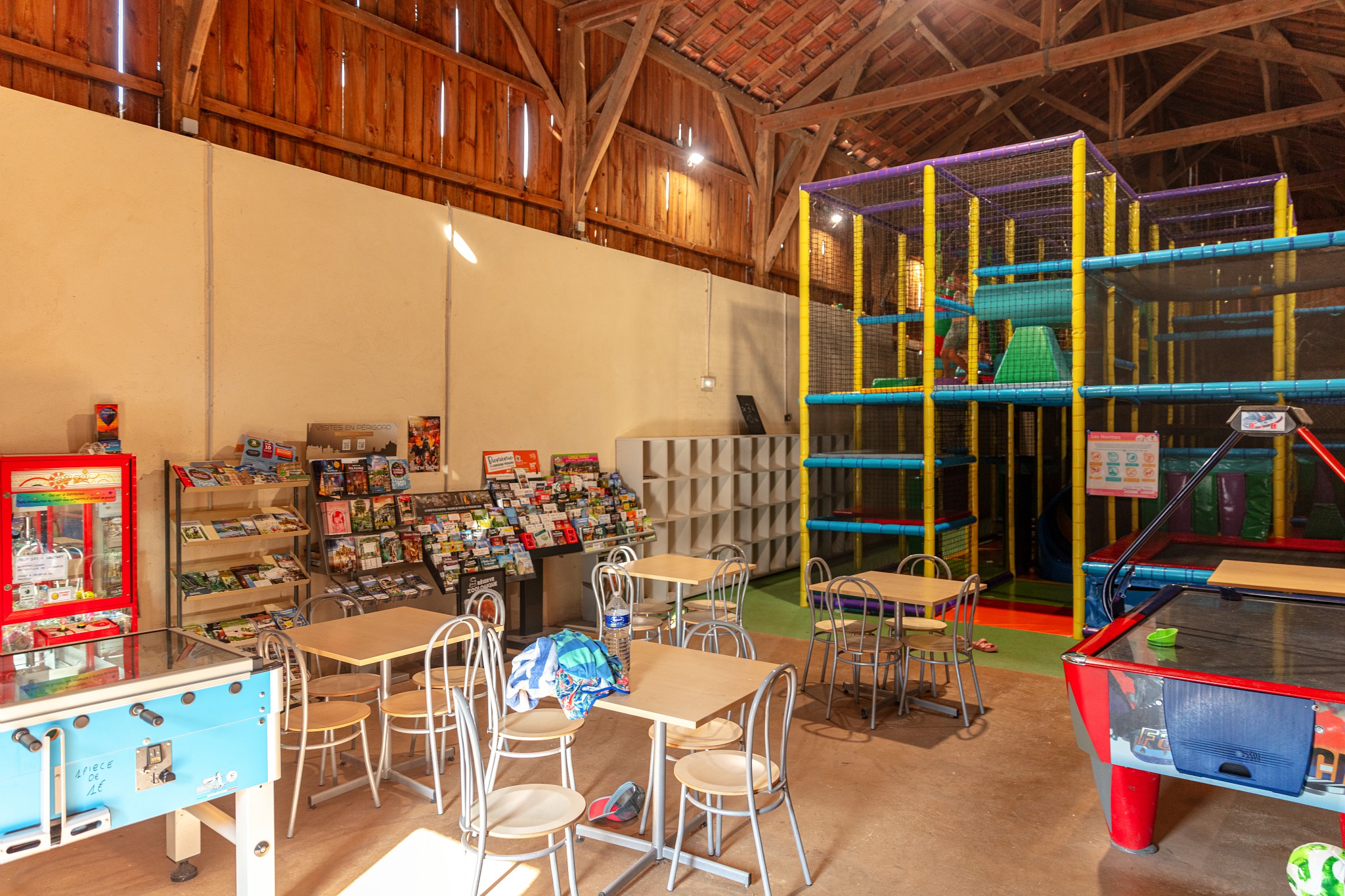 At Marvilla Parks Domaine de Soleil Plage, there is an indoor play zone featuring vibrant climbing frameworks and slides, encircled by arcade games, tables, and seating.