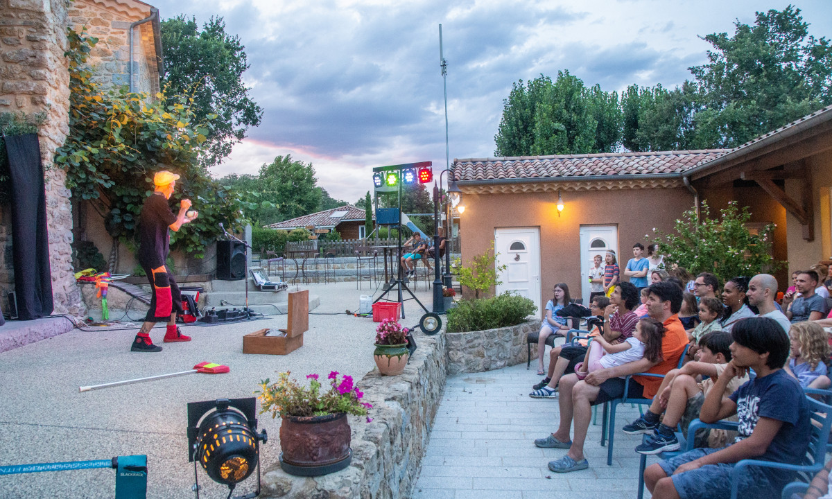 Performer juggling on an outdoor stage before an audience at Domaine de Sévenier