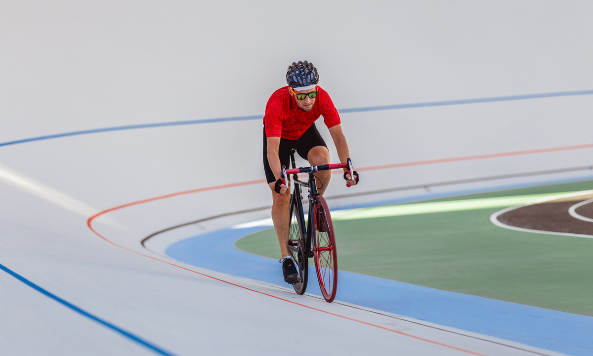 At Urban Gardens Gent, a cyclist dressed in a crimson shirt and helmet is pedaling along a path marked with vibrant lines.