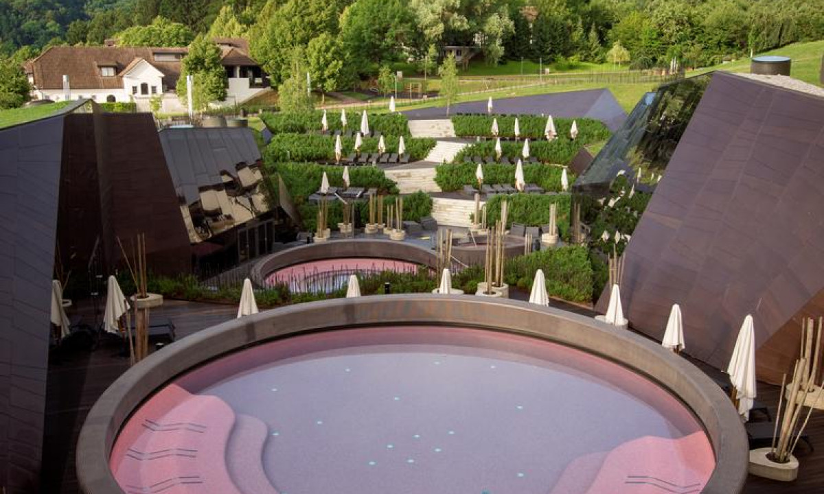 Empty round pools surrounded by closed umbrellas and modern buildings, nestled in lush, hilly countryside at Hotel Sotelia