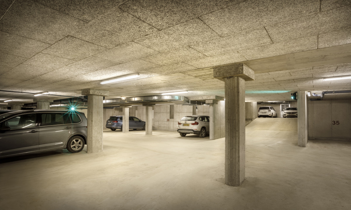 Cars parked motionless in spacious, well-lit underground garage with concrete pillars and a smooth floor at Valamar Obertauern Hotel