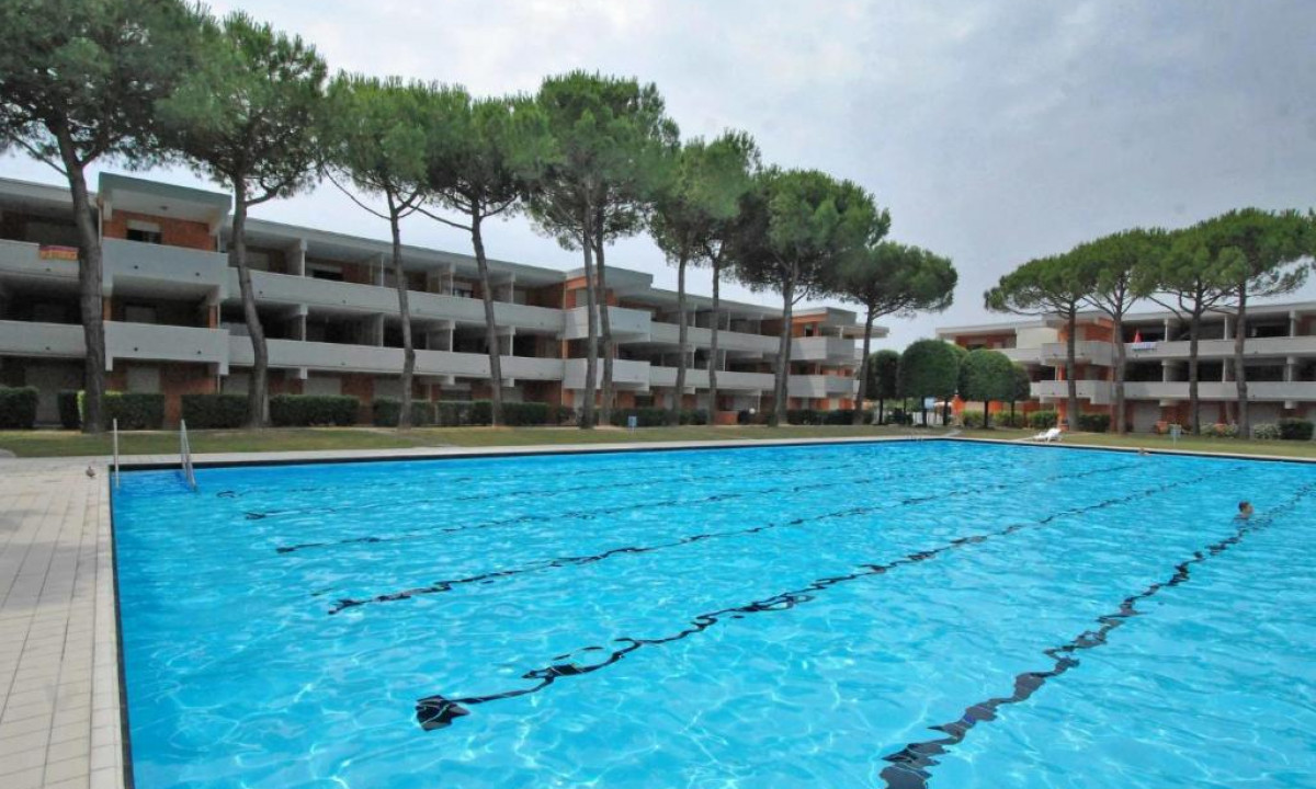 Swimming pool reflecting a clear sky, surrounded by multi-story buildings and trees in an outdoor leisure area at Solarium