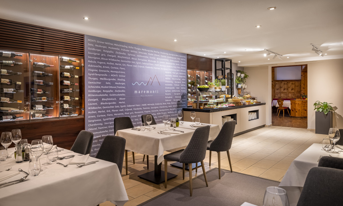 Dining tables set with glassware and cutlery, surrounded by elegant interior with wine displays at Valamar Obertauern Hotel