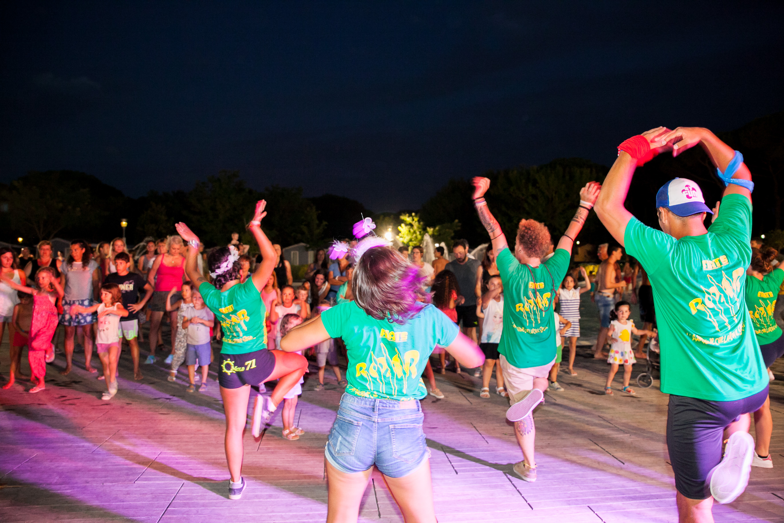People in green shirts dancing energetically, surrounded by a crowd at Pineta Sul Mare Camping Village