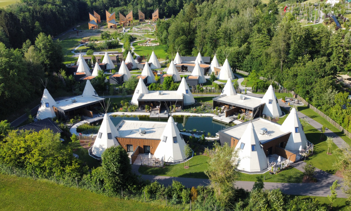 Teepee-style tents arranged in a circular pattern, surrounded by trees and pathways at Ikuna Naturresort